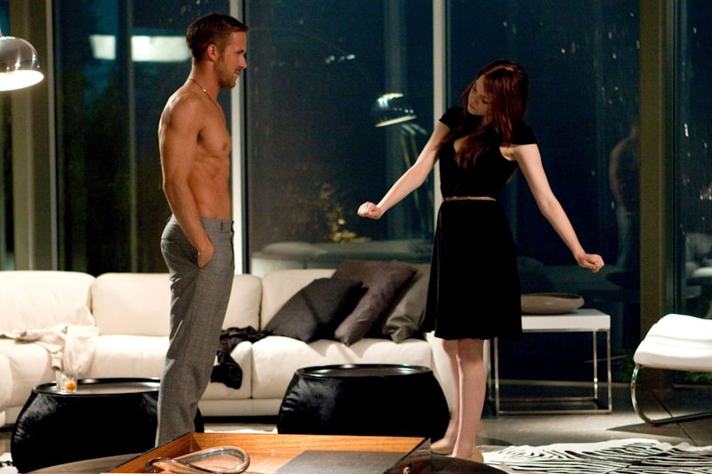 A shirtless man and a woman standing in a living room.