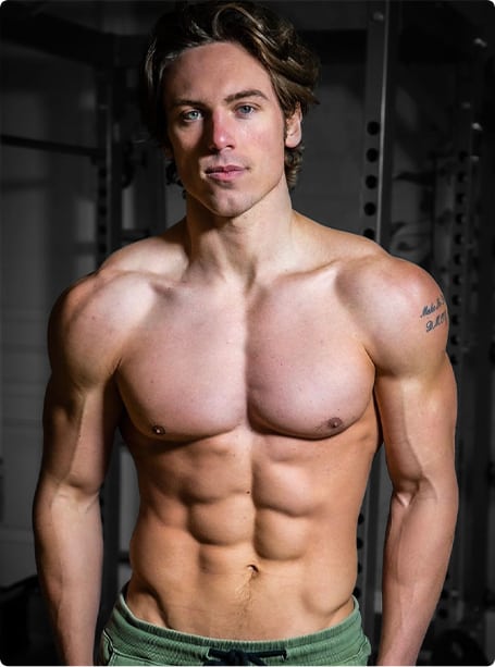 A man with a shirtless body posing in a gym.